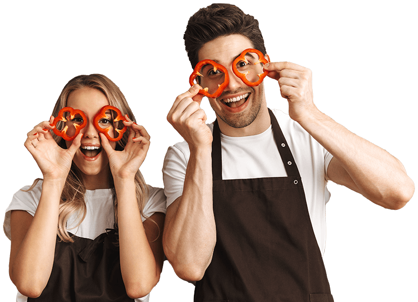 Two chefs having fun demonstrating by wearing chopped bell peppers as glasses and smiling